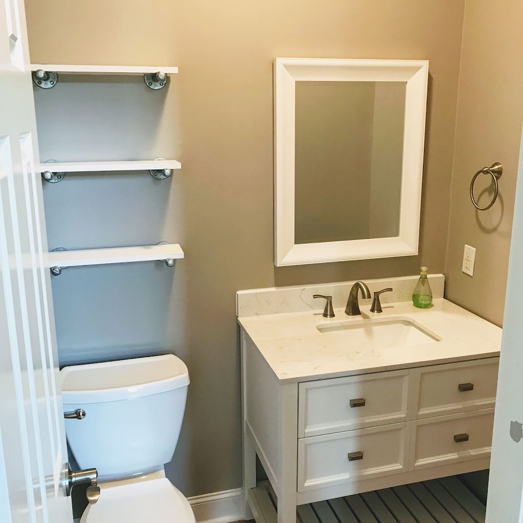 White marble-top vanity beneath industrial floating wall shelves.